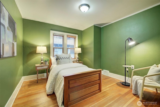 bedroom with visible vents, light wood-style floors, baseboards, and ornamental molding