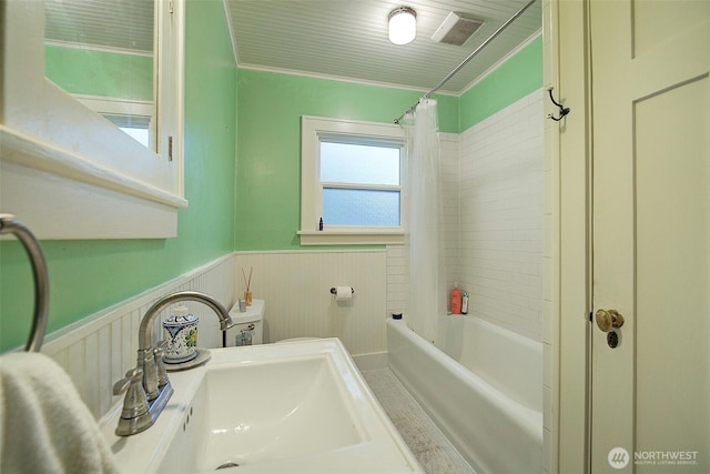 full bath with a sink, a wainscoted wall, shower / bath combo with shower curtain, and ornamental molding