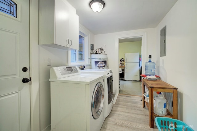 clothes washing area with electric panel, light wood-type flooring, cabinet space, and washing machine and clothes dryer