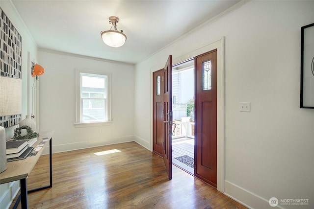 foyer entrance featuring crown molding, baseboards, and wood finished floors