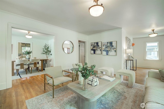 living room featuring crown molding, light wood-style flooring, and a wealth of natural light