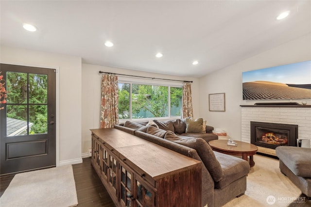 living area with recessed lighting, a brick fireplace, vaulted ceiling, wood finished floors, and baseboards