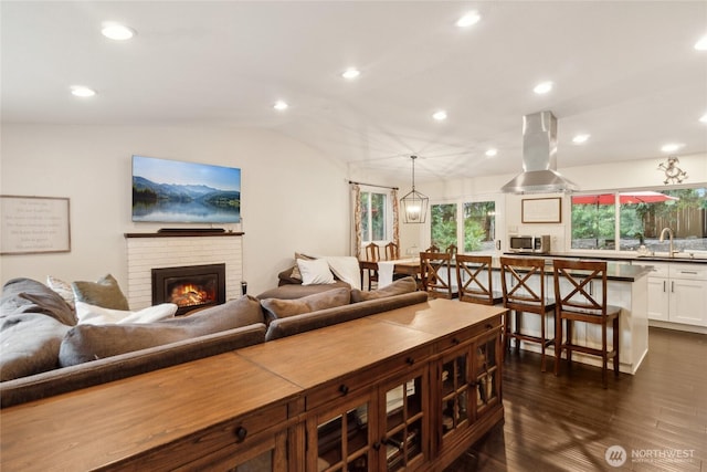 living area with recessed lighting, vaulted ceiling, a fireplace, and dark wood finished floors