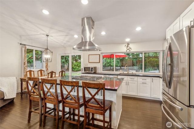 kitchen featuring island range hood, stainless steel appliances, dark wood-type flooring, white cabinetry, and dark countertops