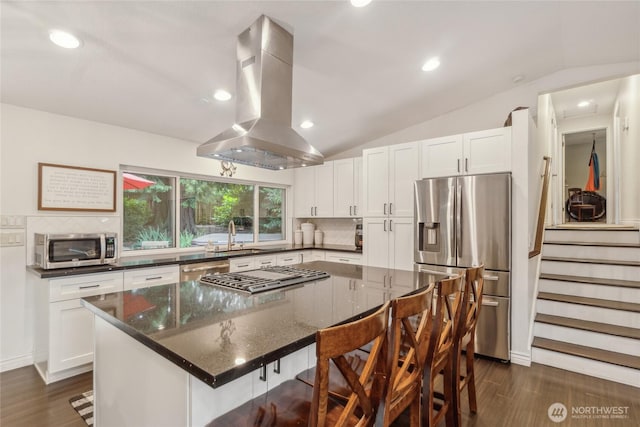 kitchen featuring vaulted ceiling, appliances with stainless steel finishes, a breakfast bar area, and island exhaust hood