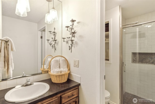 bathroom featuring a shower stall, toilet, and vanity