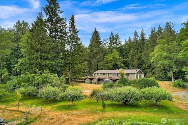 view of front of home with a deck, a front lawn, and a rural view