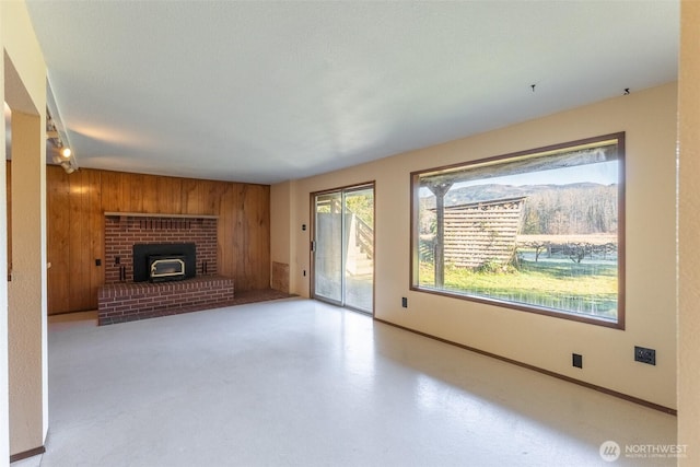 unfurnished living room featuring wooden walls and baseboards