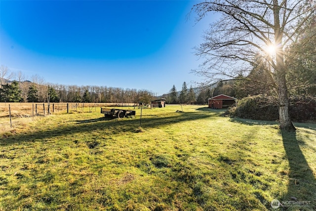 view of yard with a rural view, fence, and an outdoor structure