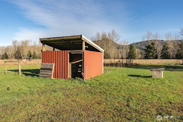 view of pole building featuring fence, a mountain view, a lawn, and a rural view