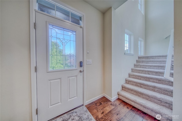 foyer with stairway, baseboards, and wood finished floors