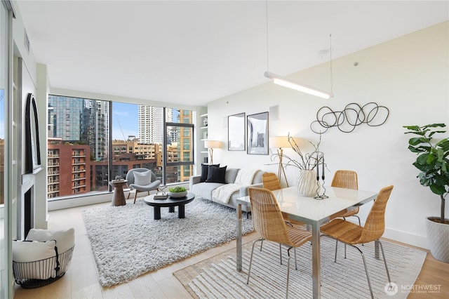 living room featuring expansive windows, baseboards, and wood finished floors