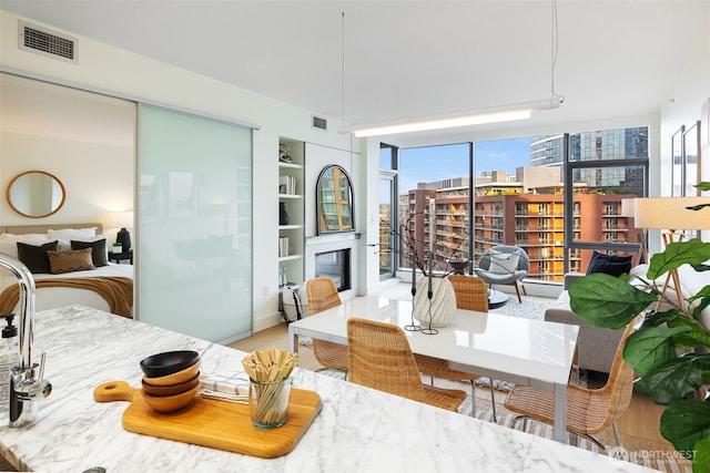 dining space featuring a view of city, visible vents, wood finished floors, and a glass covered fireplace