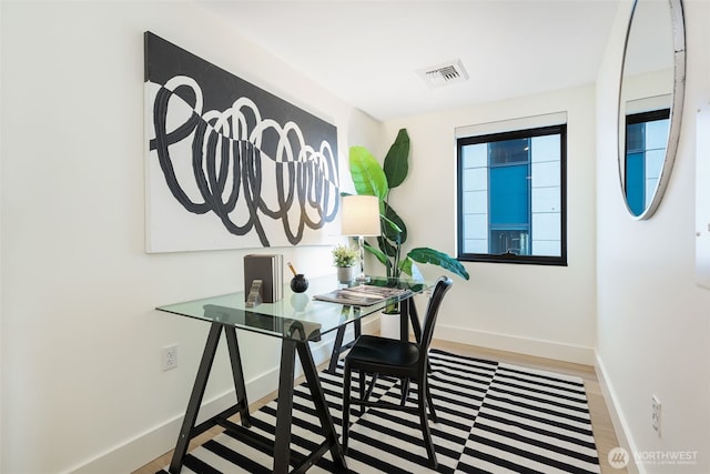 home office featuring wood finished floors, visible vents, and baseboards