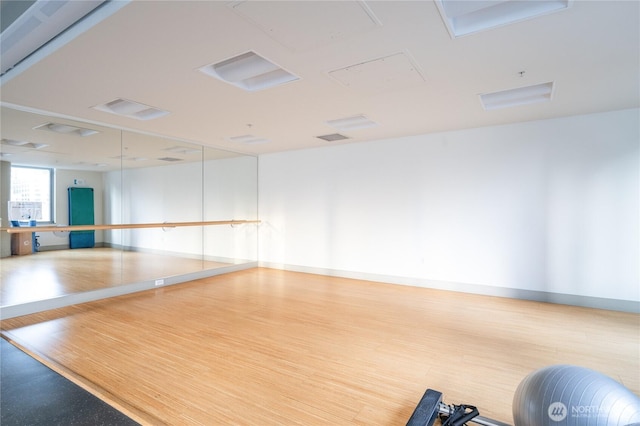 workout room with baseboards, visible vents, and wood finished floors