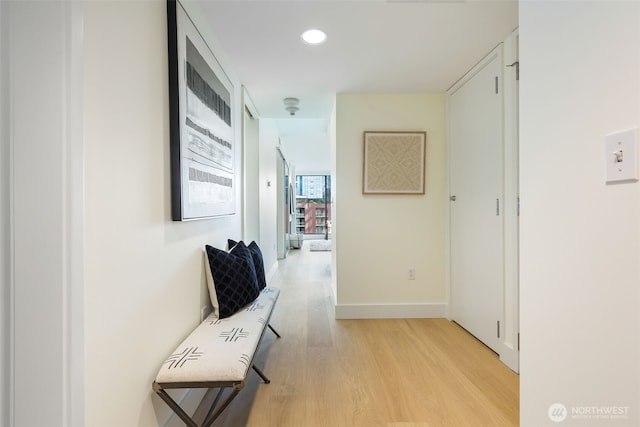 hall with light wood-style floors, baseboards, and recessed lighting