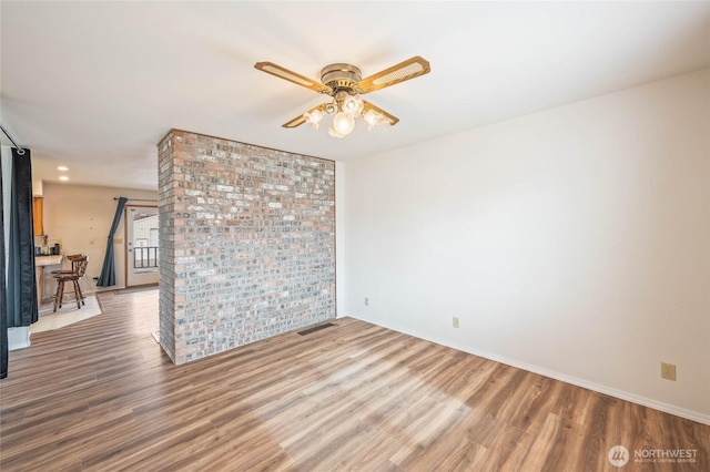 empty room featuring visible vents, ceiling fan, baseboards, and wood finished floors