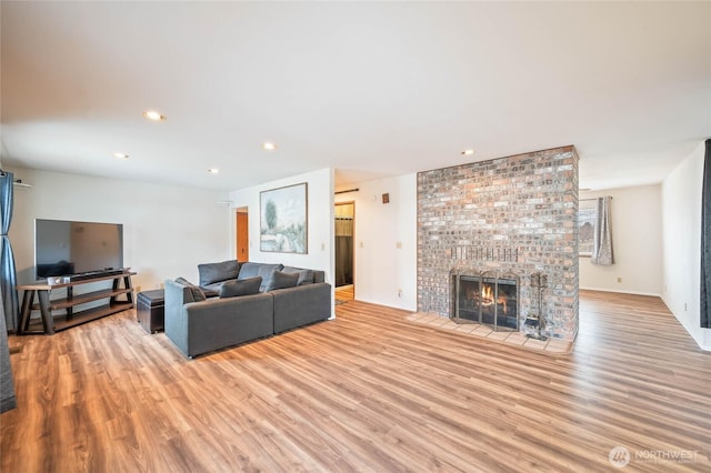 living room featuring a brick fireplace, light wood finished floors, and recessed lighting