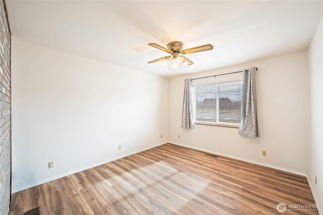 spare room with visible vents, ceiling fan, baseboards, and wood finished floors