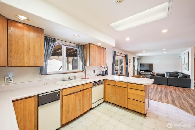 kitchen with a sink, open floor plan, light countertops, dishwasher, and light floors