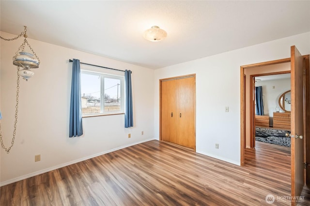 unfurnished bedroom with a closet, baseboards, and wood finished floors