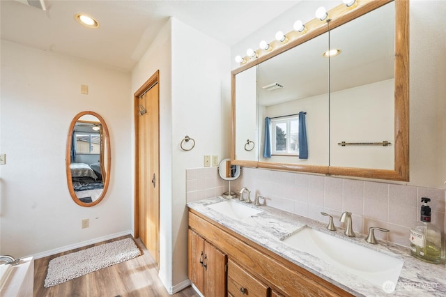 full bathroom featuring wood finished floors, backsplash, and a sink