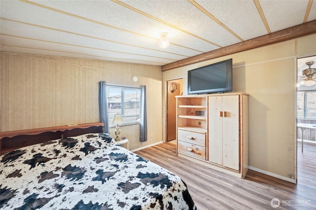 bedroom featuring a textured ceiling, baseboards, and wood finished floors