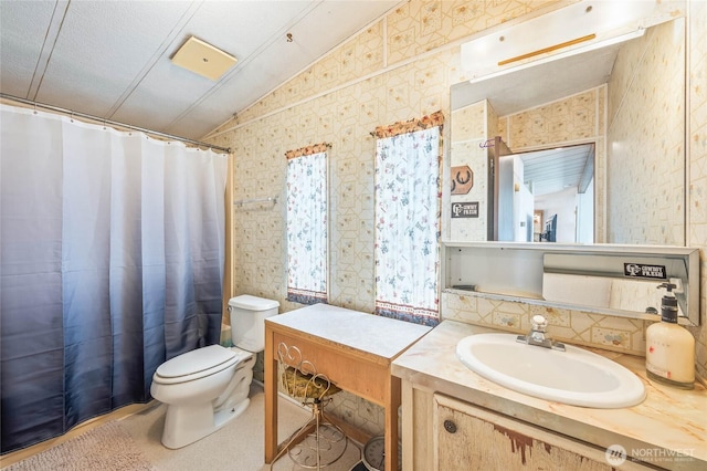 full bathroom with toilet, wallpapered walls, vanity, and lofted ceiling