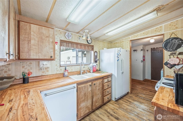 kitchen featuring dishwasher, a sink, freestanding refrigerator, and wallpapered walls