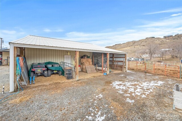 view of outbuilding featuring an outbuilding, a carport, an exterior structure, and a mountain view