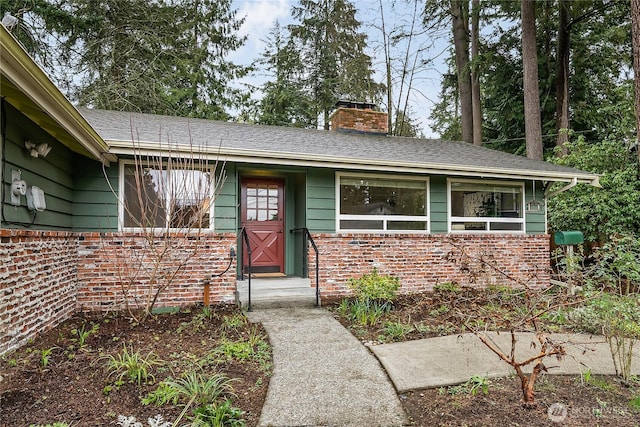 view of front of house with brick siding and a chimney