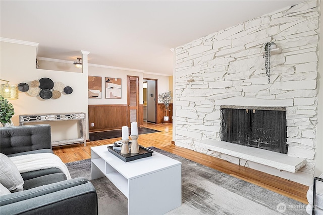 living area with a fireplace, crown molding, and wood finished floors