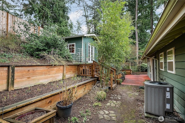 view of yard featuring a garden, cooling unit, and fence