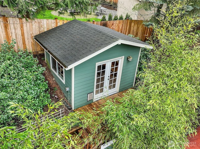 view of outdoor structure with an outbuilding, french doors, and fence