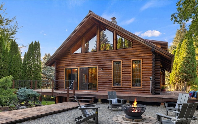 rear view of property featuring a deck, a fire pit, a patio area, and log exterior