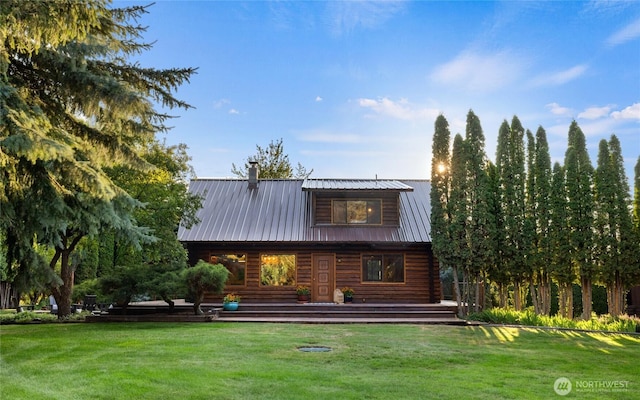 back of property with metal roof and a yard