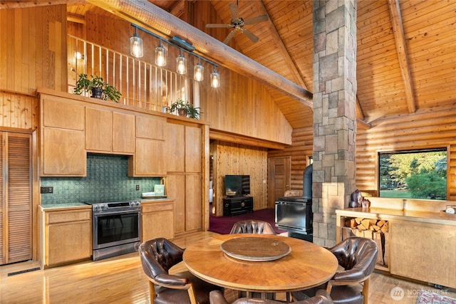 kitchen with light wood finished floors, wood ceiling, a wood stove, stainless steel range with electric cooktop, and beam ceiling