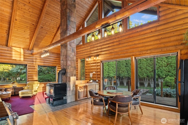 dining room with a wood stove, wooden ceiling, beam ceiling, and wood finished floors