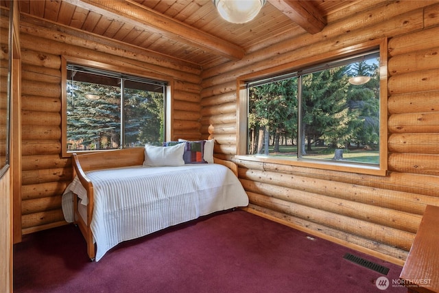 carpeted bedroom featuring visible vents, beamed ceiling, log walls, and multiple windows