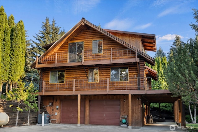 exterior space with an attached garage, a balcony, driveway, and central AC