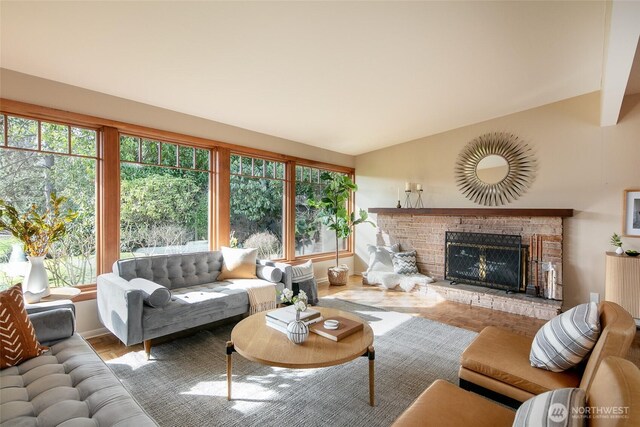 living area with lofted ceiling, plenty of natural light, and a stone fireplace