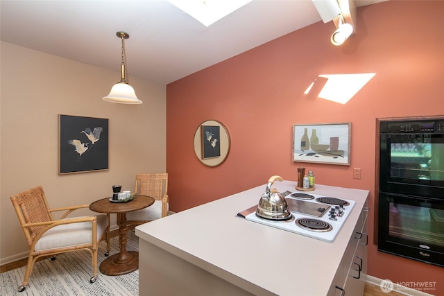 kitchen featuring a skylight, decorative light fixtures, light countertops, dobule oven black, and white electric cooktop