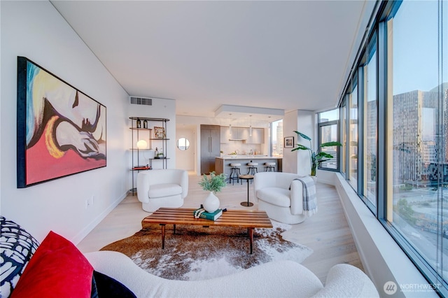 living area with light wood-style floors, visible vents, and baseboards