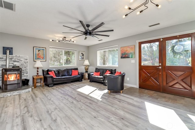 living area featuring a wood stove, visible vents, wood finished floors, and french doors