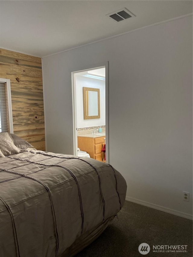 bedroom with wooden walls, baseboards, visible vents, connected bathroom, and carpet floors