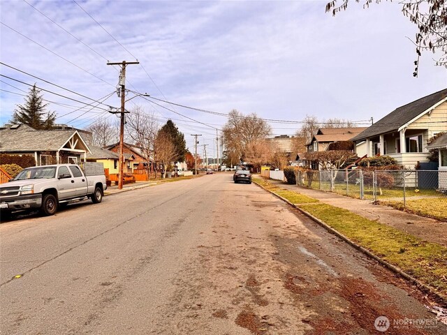 view of street featuring street lights, curbs, sidewalks, and a residential view