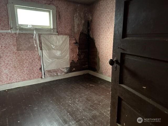 unfurnished room with baseboards, hardwood / wood-style floors, and wallpapered walls