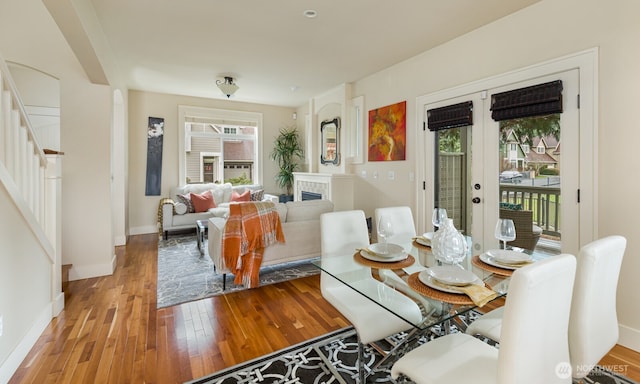 dining area with baseboards, wood-type flooring, stairs, and french doors