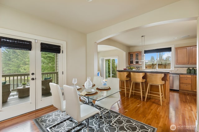 dining area with french doors, arched walkways, and wood-type flooring