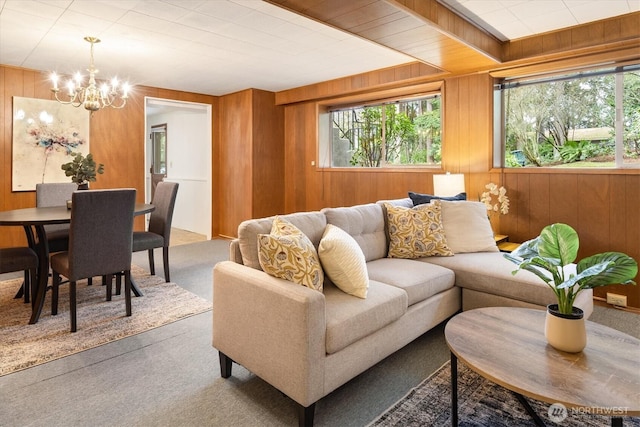 carpeted living room featuring an inviting chandelier and wood walls